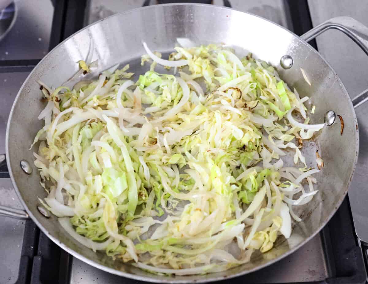 Overhead shot of cabbage and onions sautéing in a skillet, 