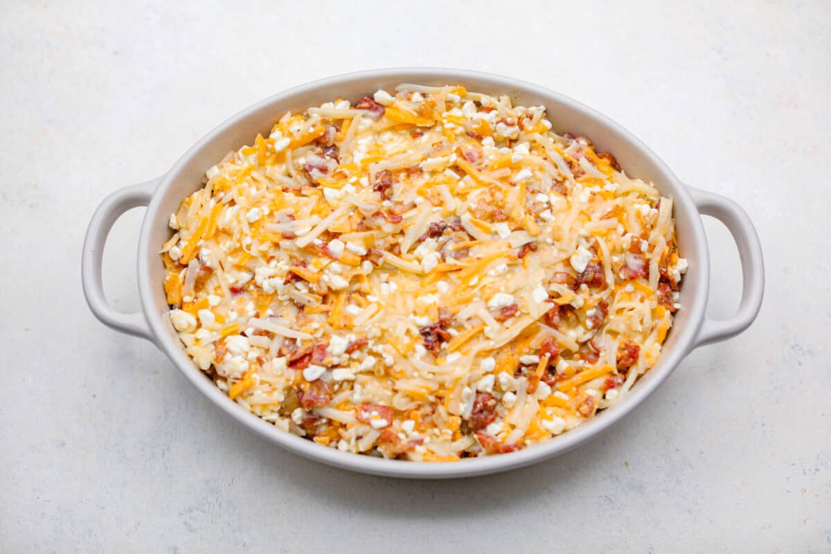 Overhead shot of amish breakfast casserole ingredients in a baking dish ready to be cooked. 