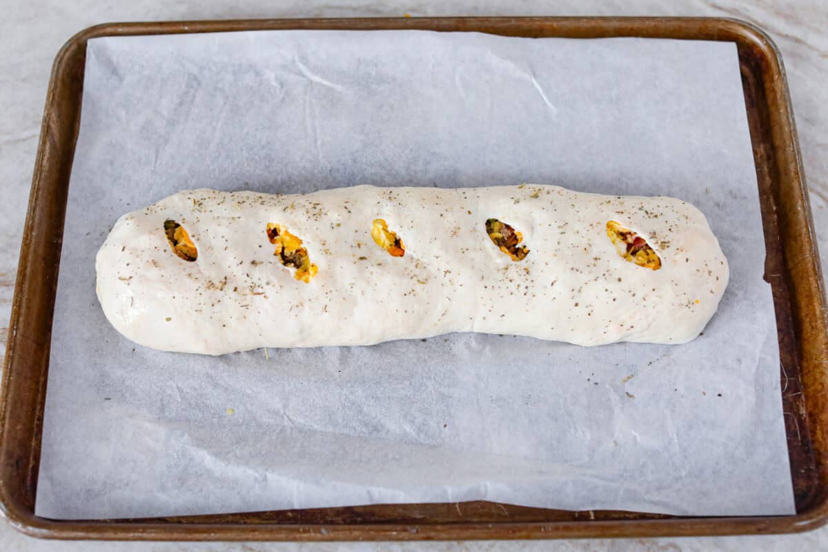 Overhead shot of the breakfast Stromboli with slits in the top and toped with italiand seasoning and garlic powder. 