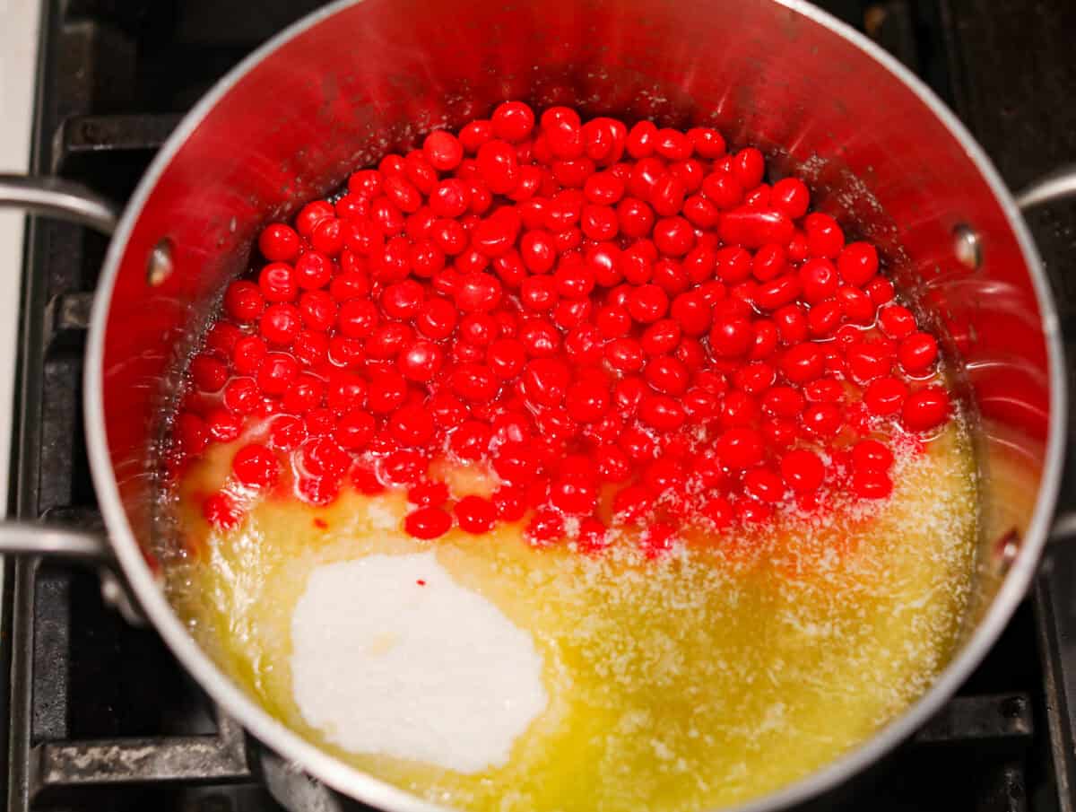 Overhead shot of sugar, corn syrup, salt and red hots candies added to the melted butter. 