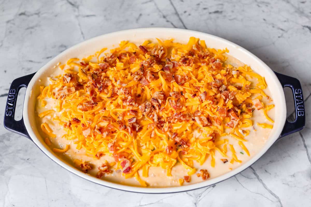 Loaded scalloped potatoes are rich, creamy, and Overhead shot of cheese and bacon sprinkled over the top of the potatoes and sauce.