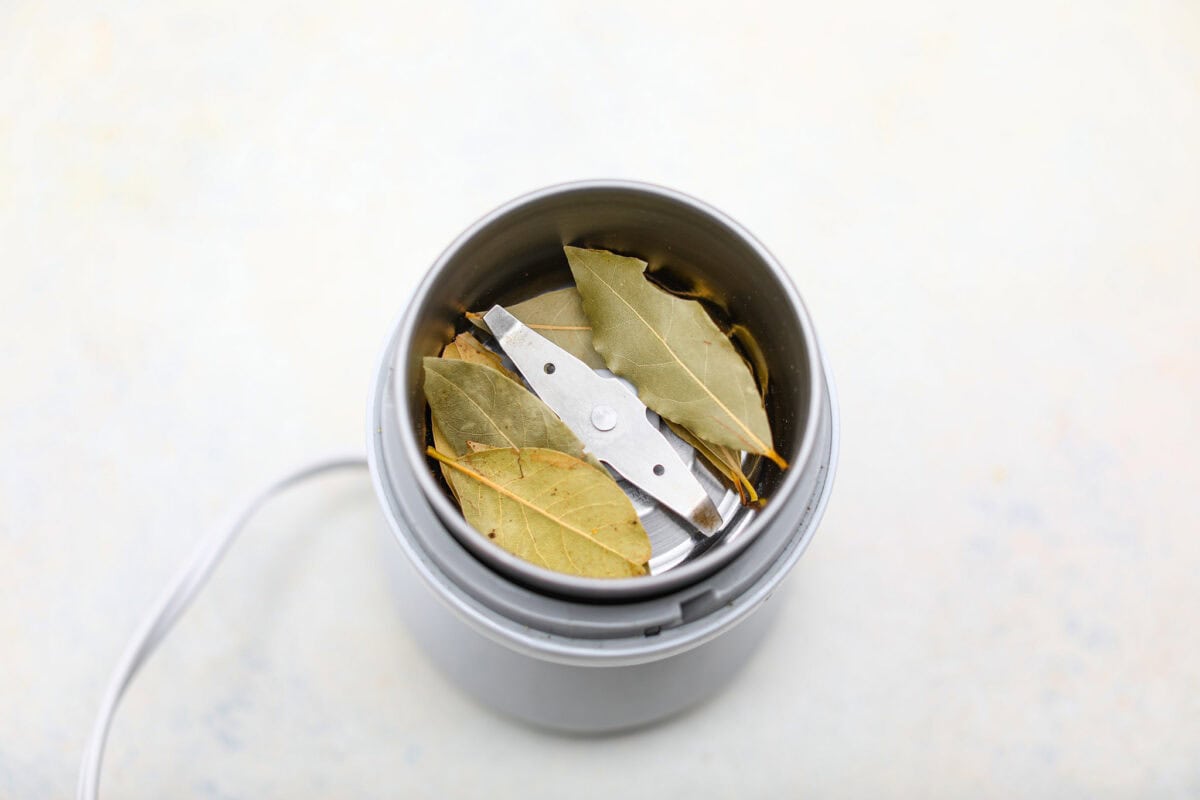 Overhead shot of bay leaves in a spice or coffee grinder. 