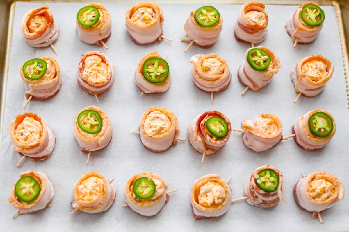 Overhead shot of the filled, bacon wrapped sausage cups.  Some of the pig shots have a slice of jalapeño on top. 