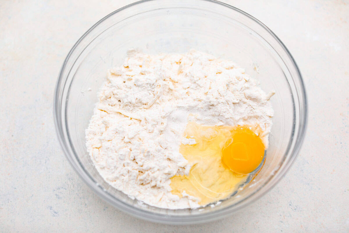 Overhead shot of the butter and dry ingredient mixture with an egg on top.