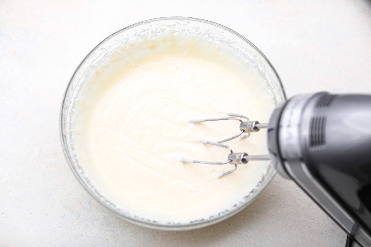 Overhead shot of the ricotta cheese being blended together with a hand mixer. 