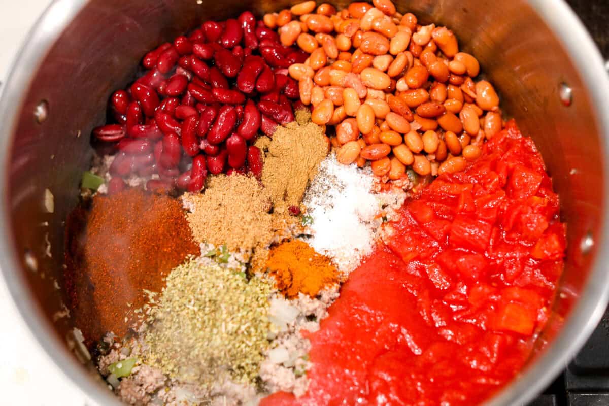 Overhead shot of beans, tomatoes and seasonings in the pot with the ground turkey and veggies.