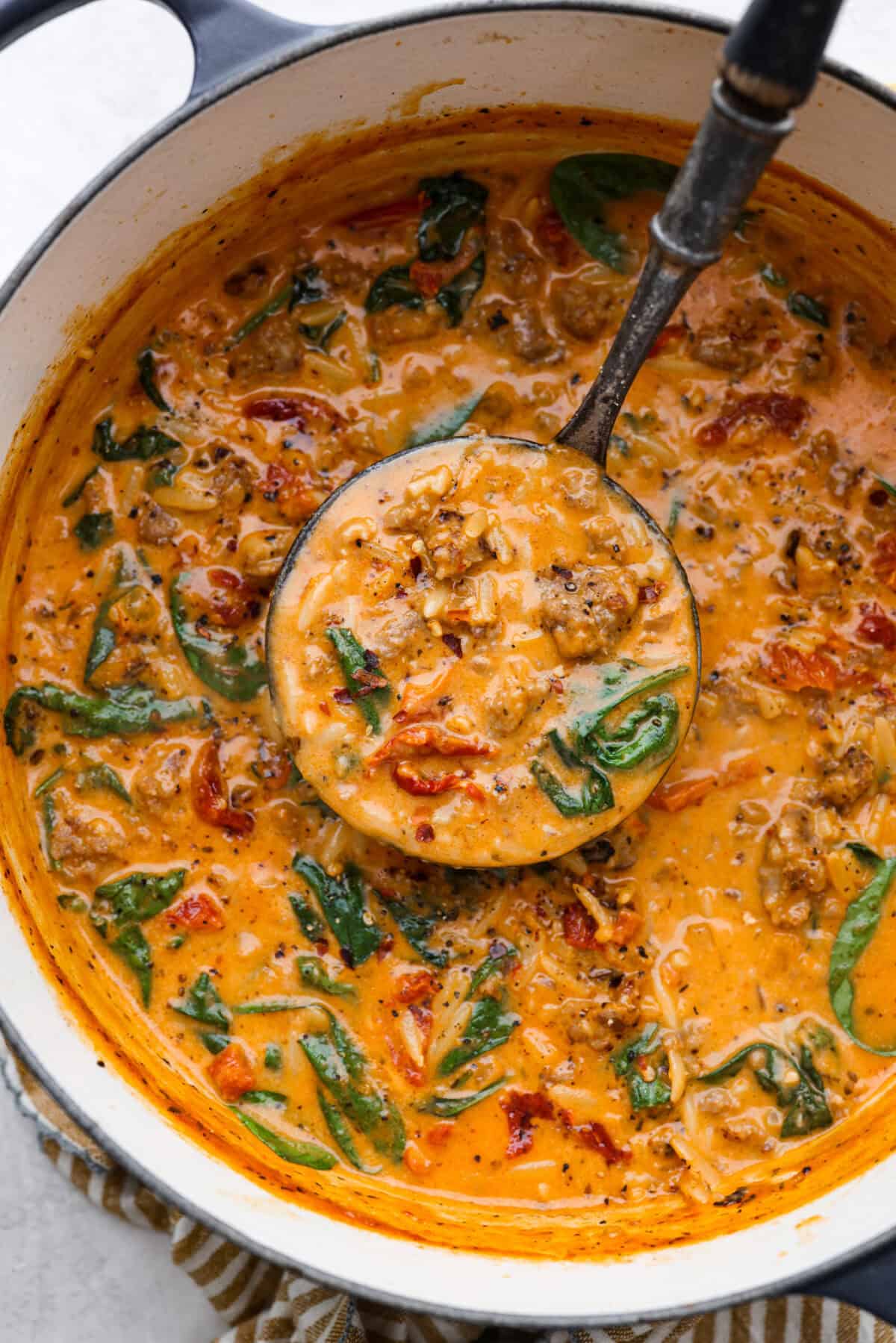 Overhead shot of marry me sausage orzo soup in a pot with a ladle. 