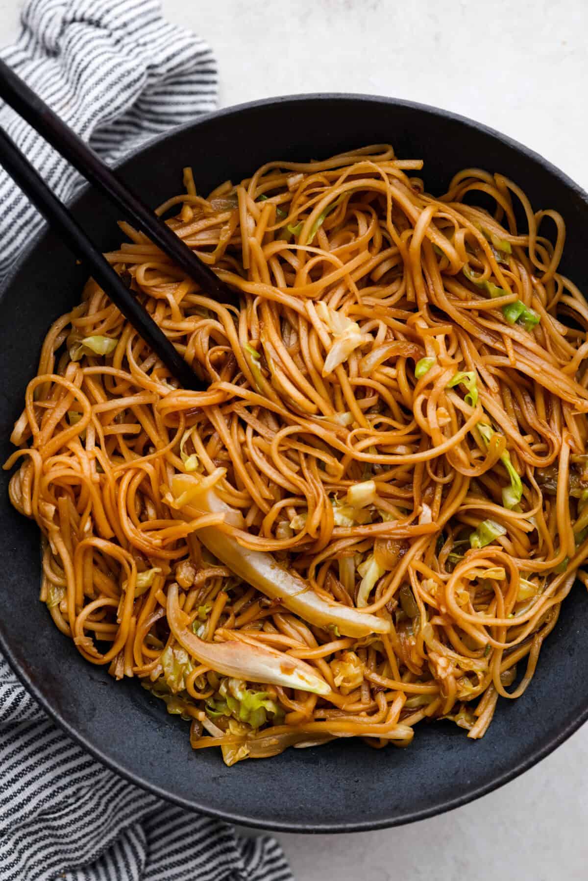 Overhead shot of a bowl of Panda Express low mein with chopsticks. 