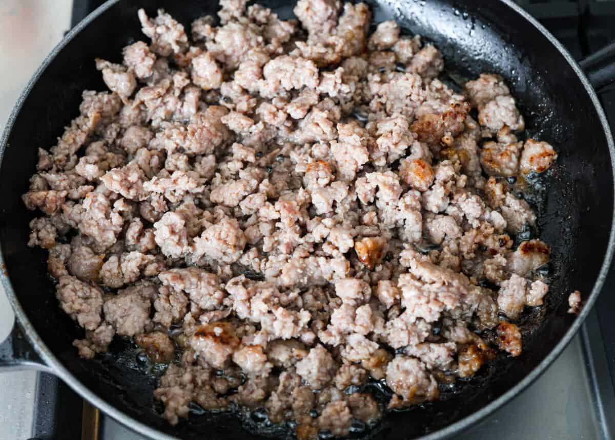 Overhead shot of sausage cooking in a pan. 