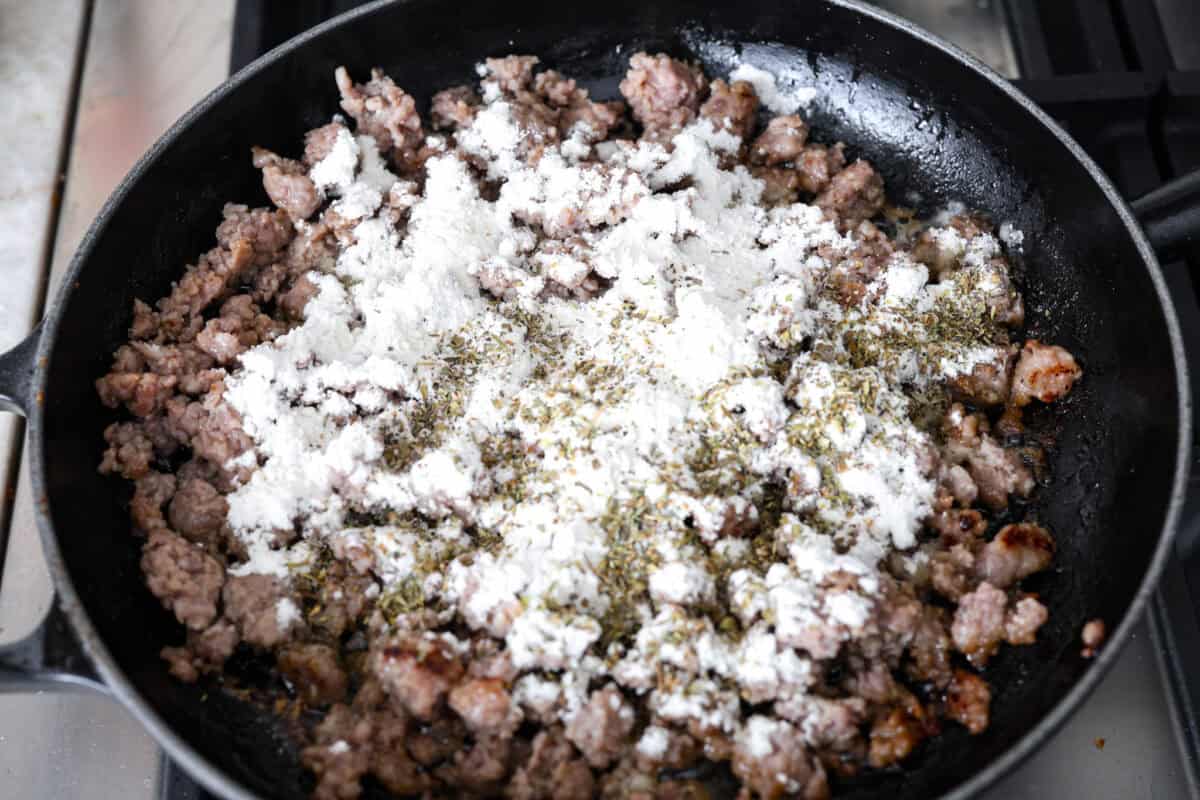 Overhead shot of cooked sausage with flour and seasonings added to it. 