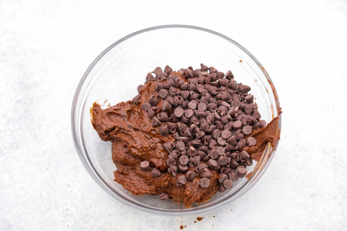 Overhead shot of black bean brownie batter in a mixing bowl with chocolate chips added to it. 