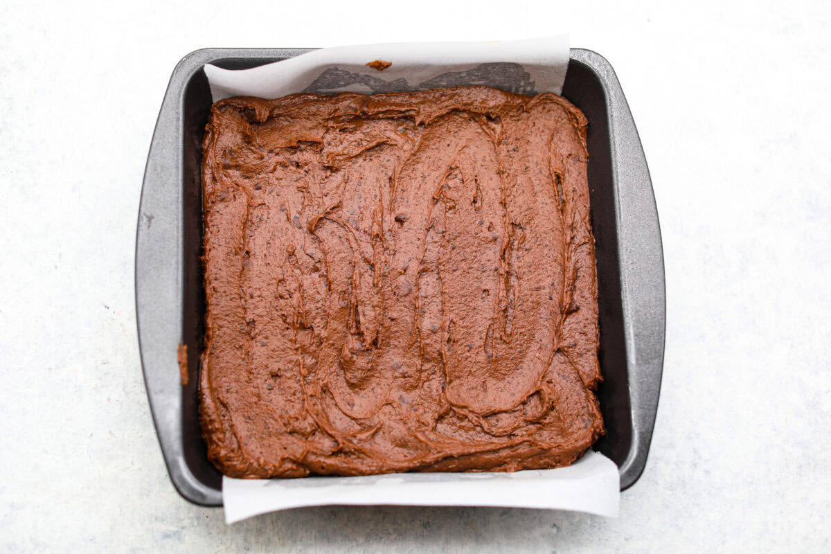 Overhead shot of brownie batter spread in the bottom of the prepared pan. 