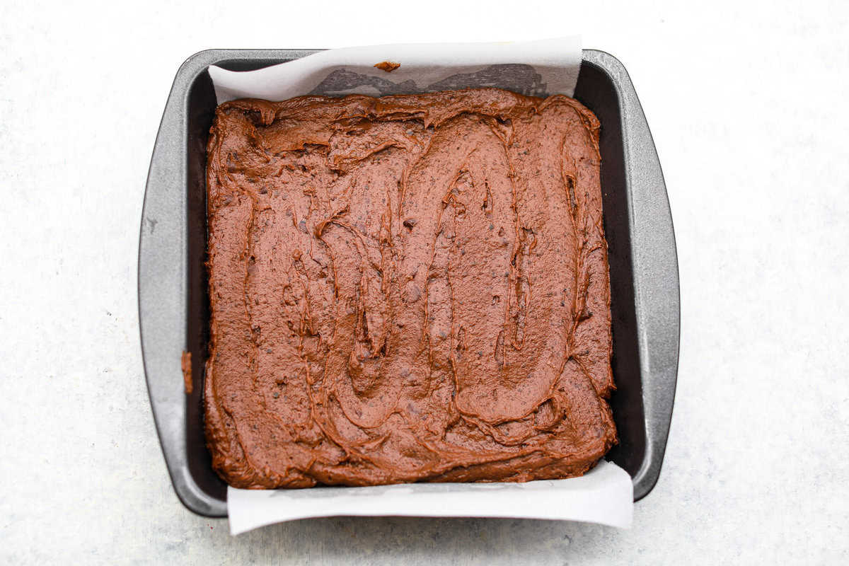 Overhead shot of brownie batter spread in the bottom of the prepared pan.