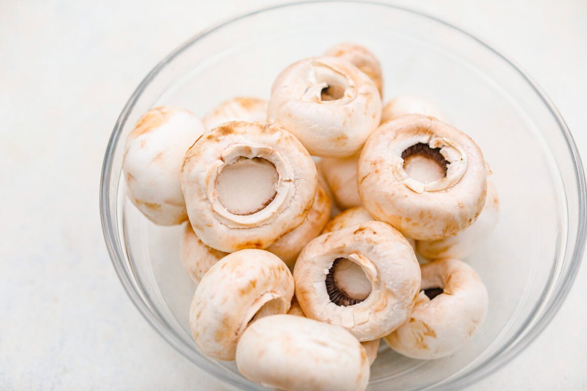 Overhead shot of washed mushrooms with their stems removed in a bowl. 