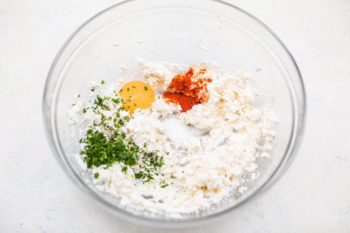 Overhead shot of the whisked cream cheese with egg yolk, paprika and salt in a mixing bowl. 