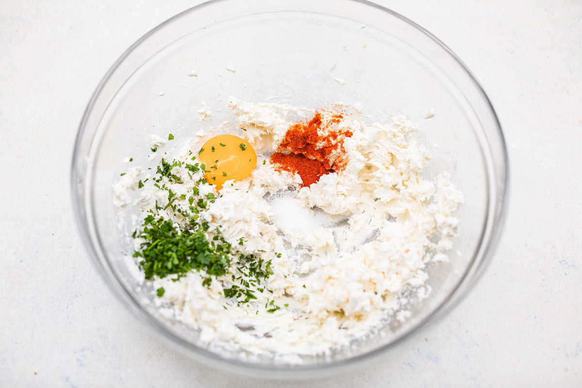 These Crab Stuffed Mushrooms are a deliciously savory appetizer, perfect for impressing guests at any gathering. With a rich crab filling in every bite, they’re sure to be a crowd favorite! Overhead shot of the whisked cream cheese with egg yolk, paprika and salt in a mixing bowl.