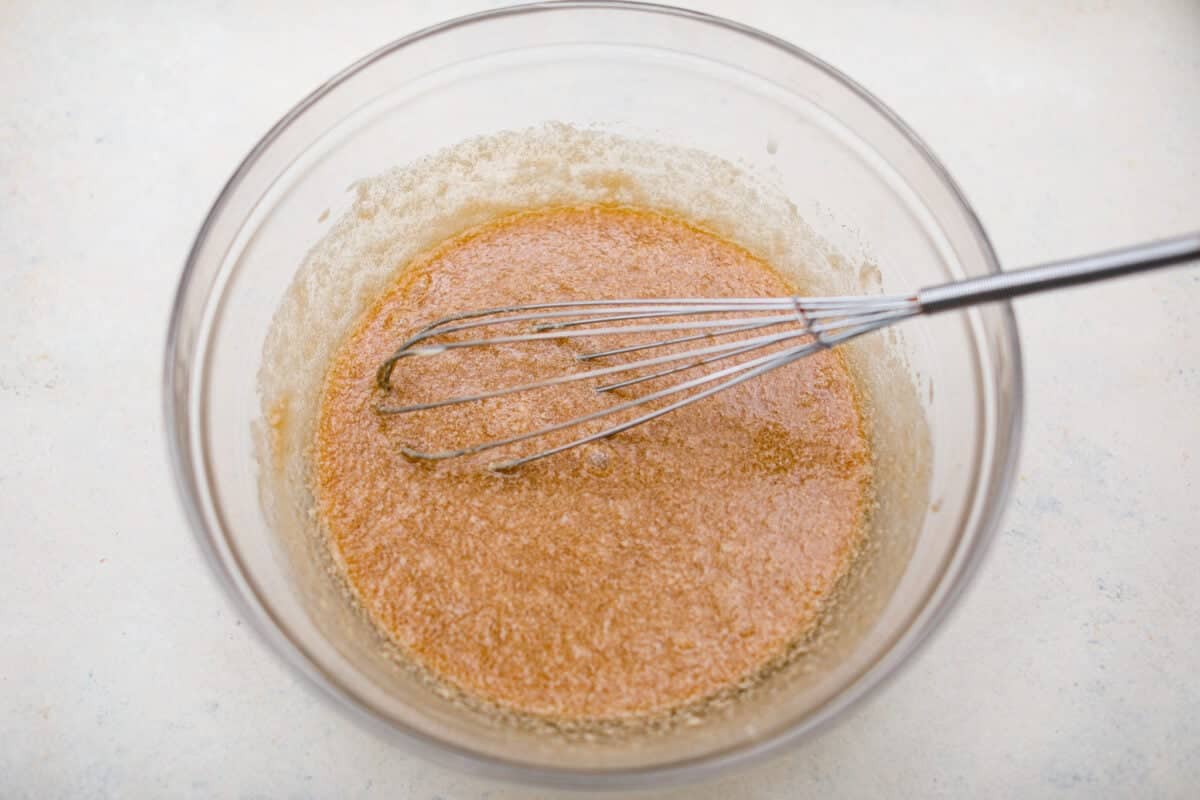 Overhead shot of oil, butter, Guinness, and sugar whisked in a large mixing bowl. 