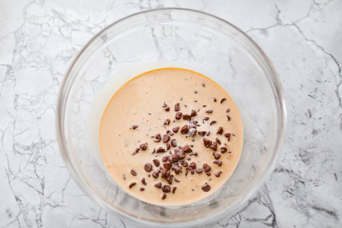 Overhead shot of warmed Guinness and whipping cream poured over the chocolate chips in a bowl. 