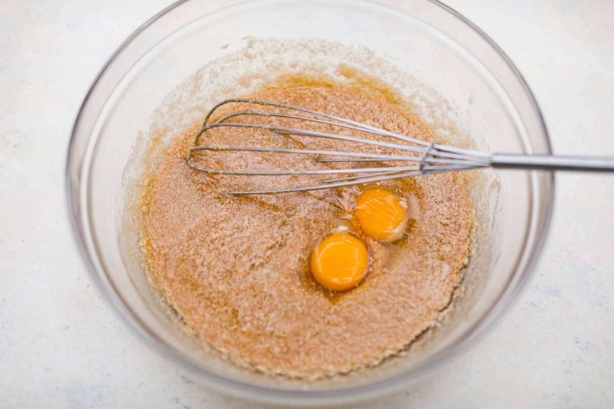 Overhead shot of eggs and vanilla added to the other whisked brownie ingredients. 