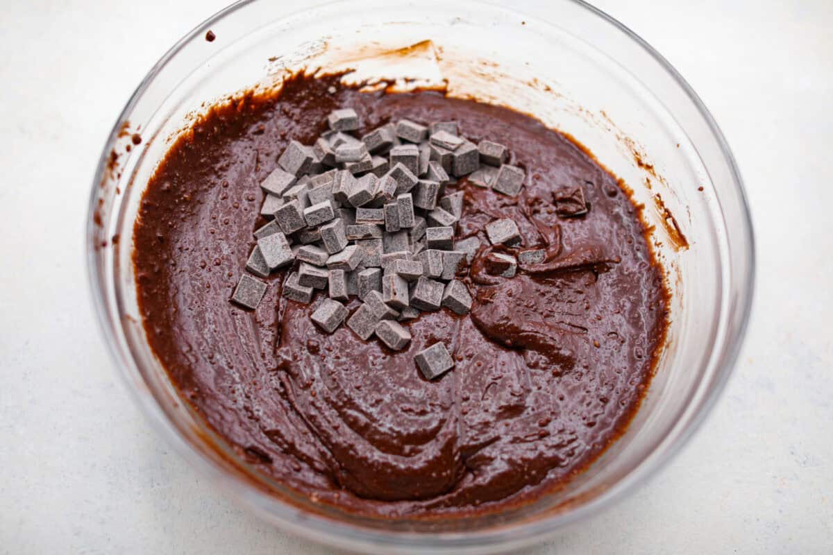 Overhead shot of chocolate chunks added to the mixed brownie batter. 