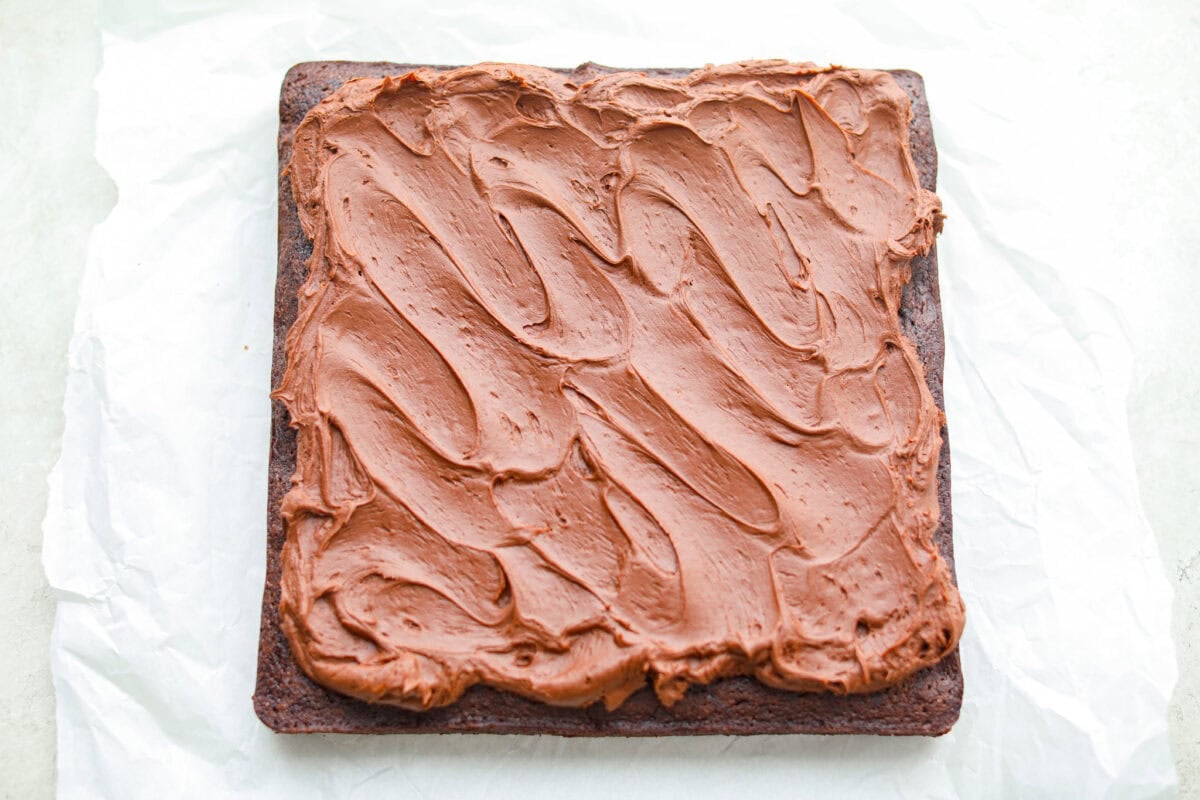 Overhead shot of baked and frosted Guinness brownies on a piece of parchment paper. 