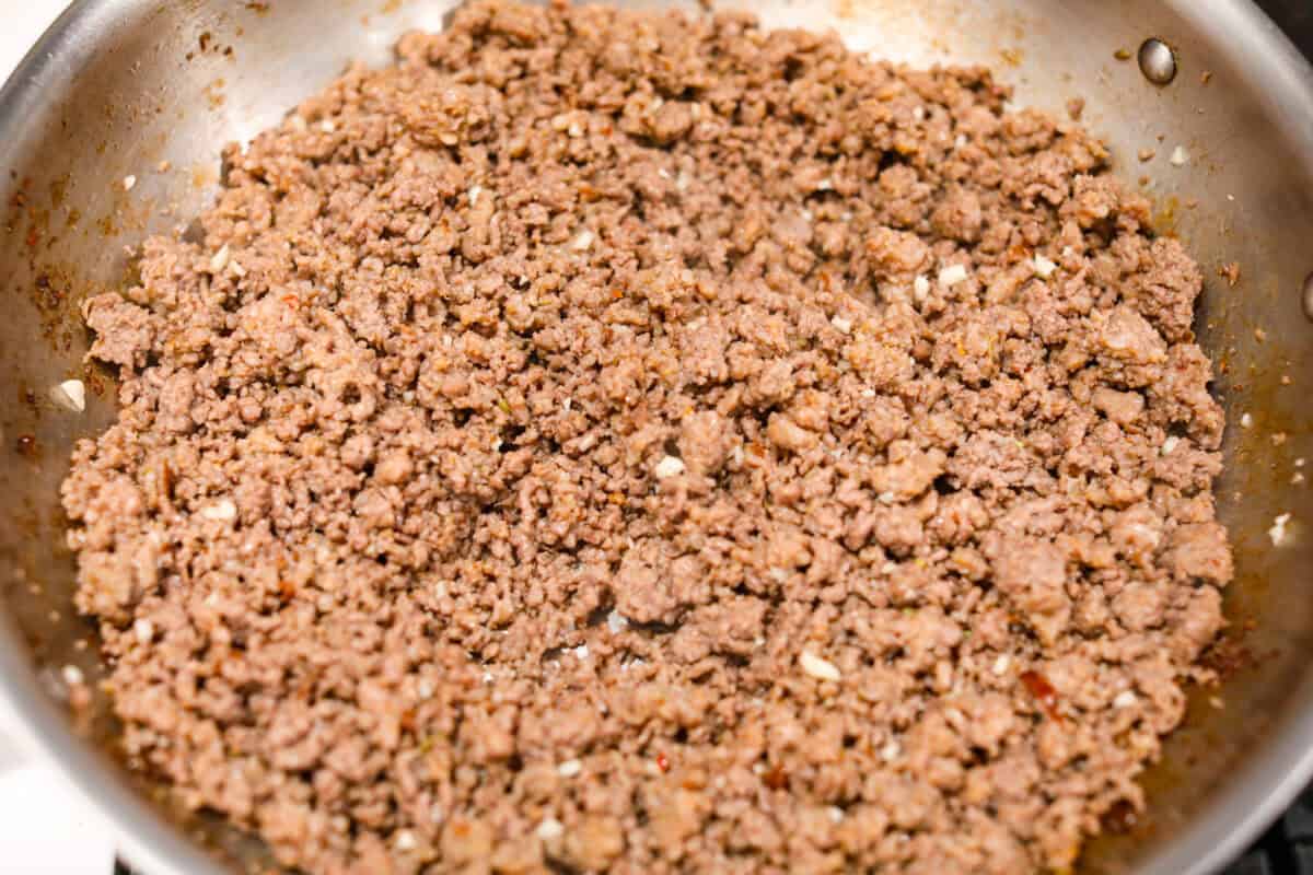 Overhead shot of garlic added to the cooked meat. 