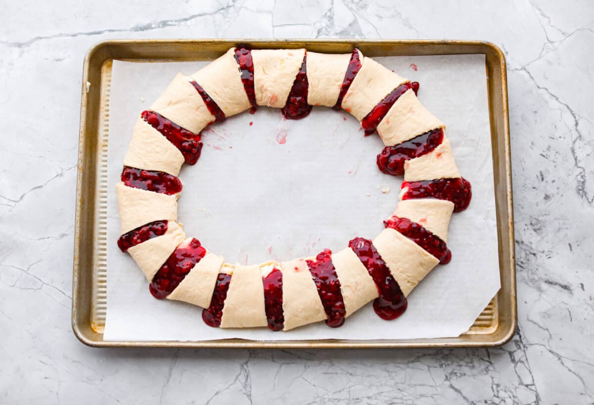 Overhead shot of the crescent rolls wrapped around the top of the raspberry and cream cheese filling to make a ring. 