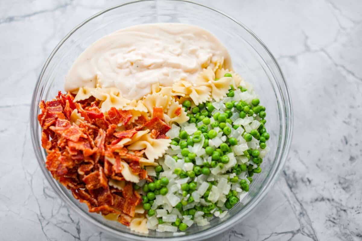 Overhead shot of the bacon, pasta cooked veggies and sauce in a bowl. 