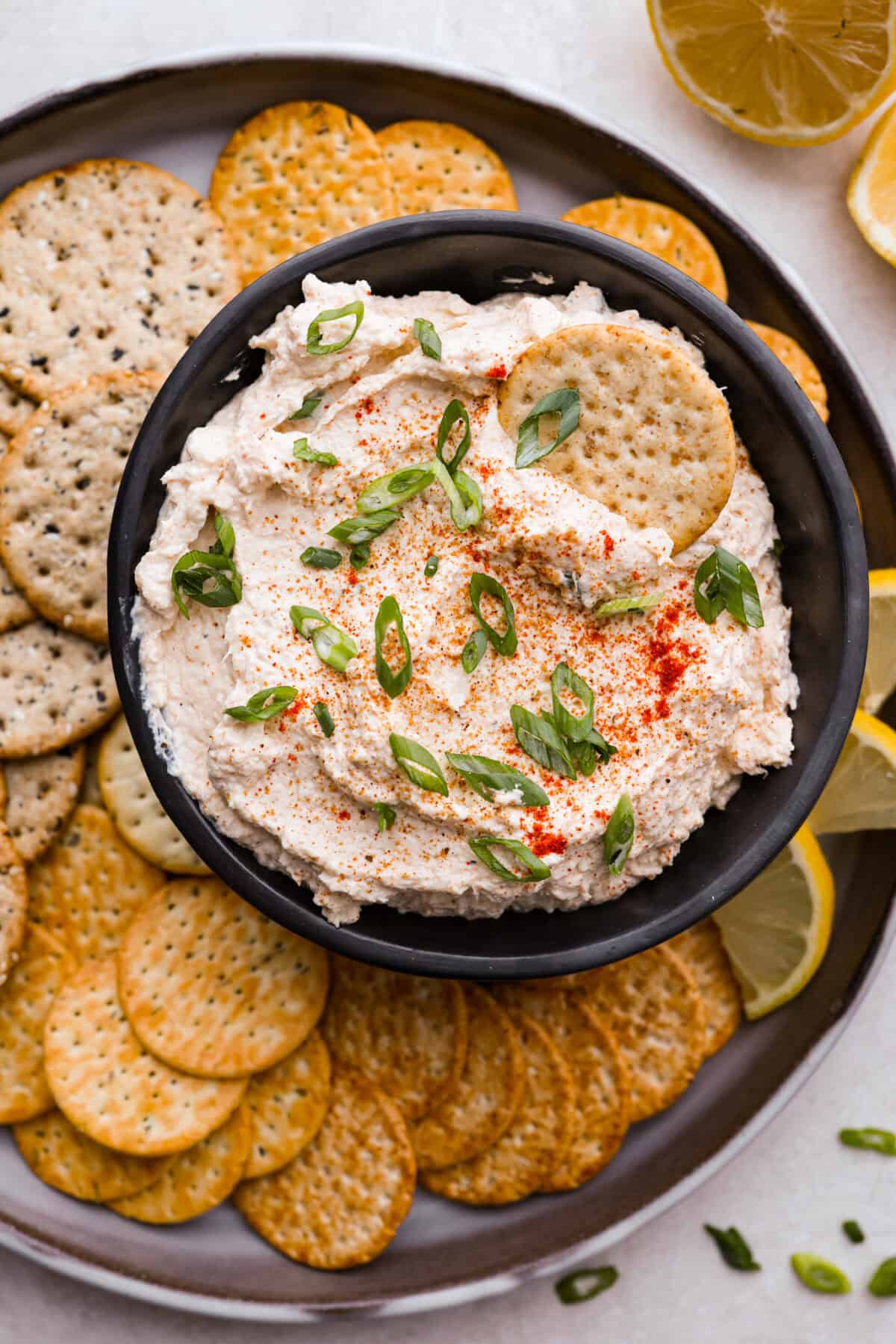 Overhead shot of cajun crab dip in a bowl on a serving platter full of crackers. 