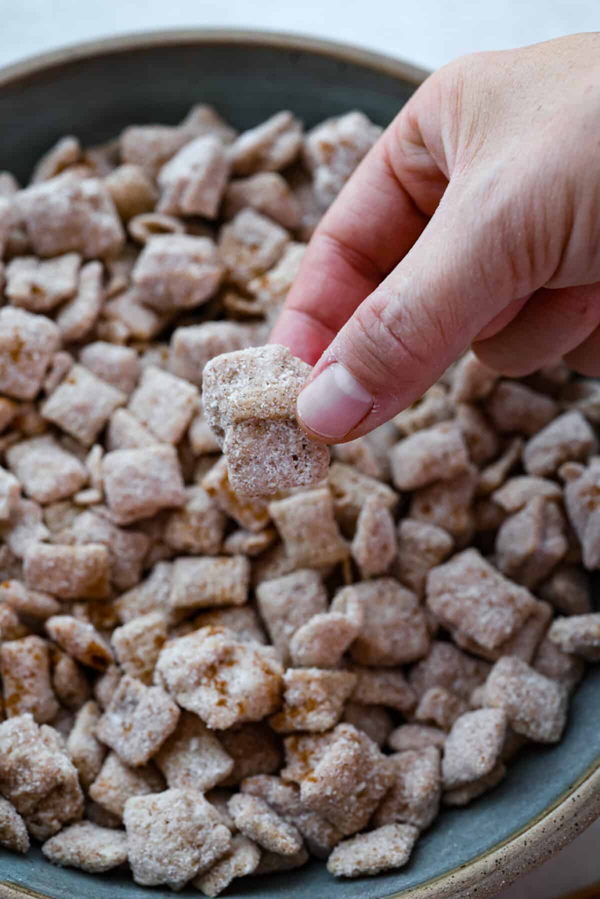 Close up shot of someone picking up a chunk of the churro Chex mix. 