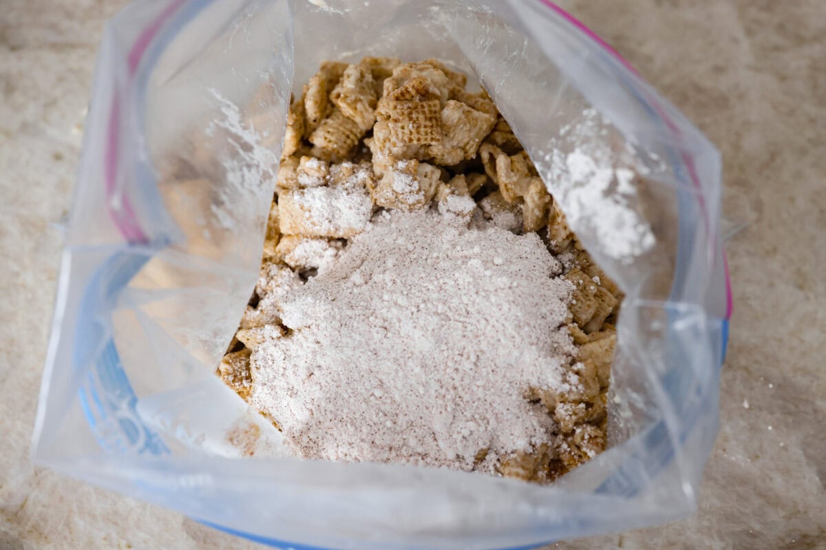 Overhead shot of the chocolate covered cereal in a large ziplock with the cinnamon and sugar mixture poured over the top. 