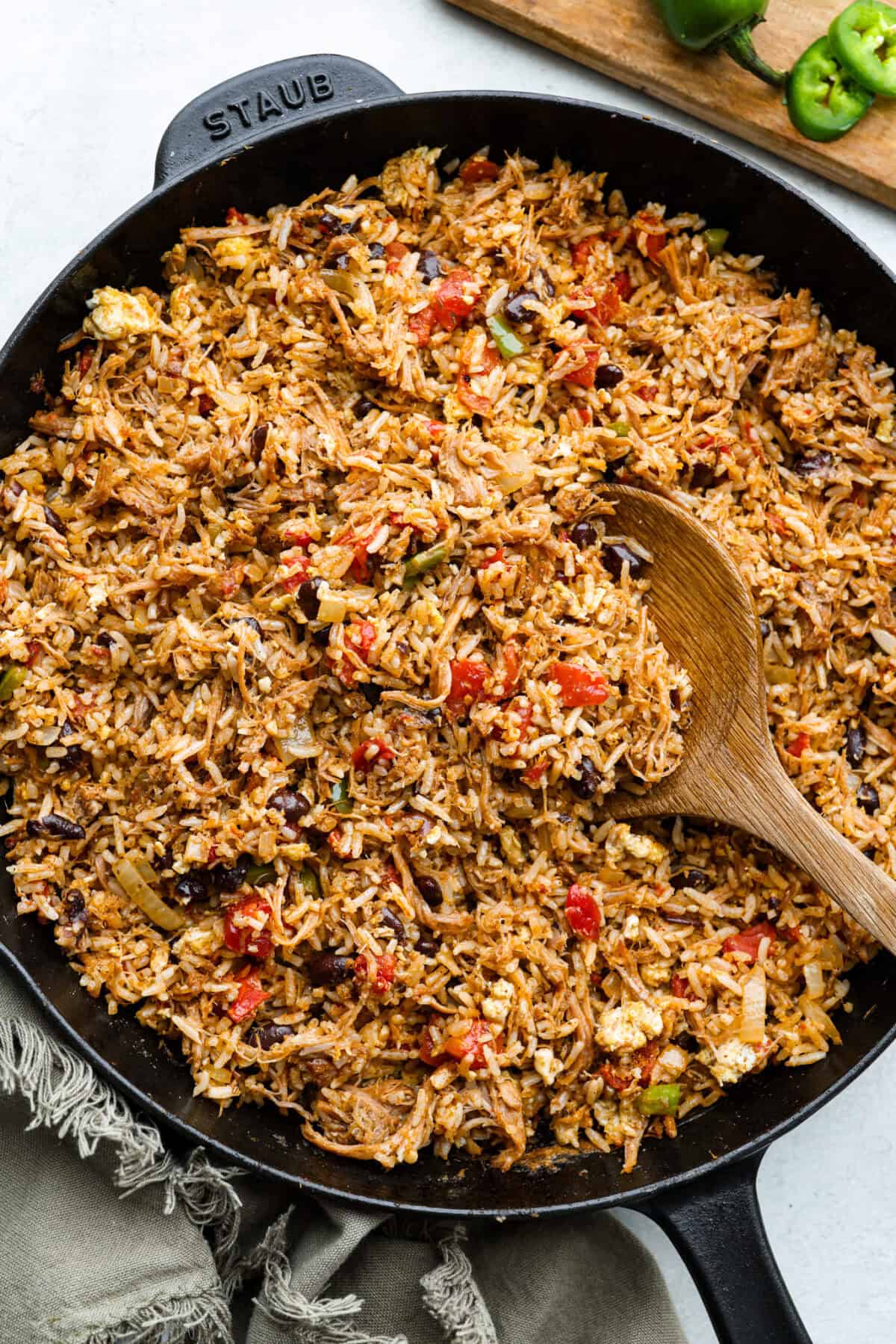 Overhead shot of cowboy fried rice in a skillet with wooden spoon. 