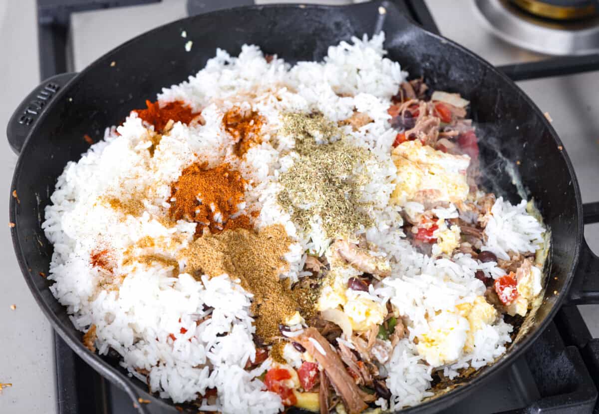 Overhead shot of pork and egg mixture with rice and seasonings added in.