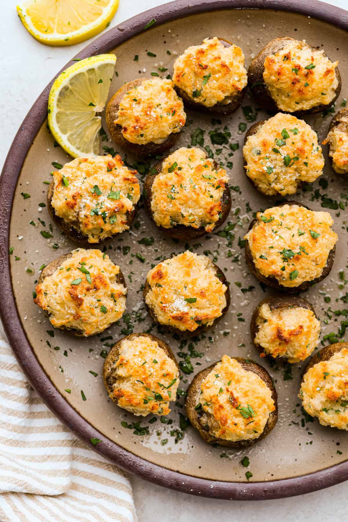 Overhead shot of baked crab stuffed mushrooms on a serving plate. 