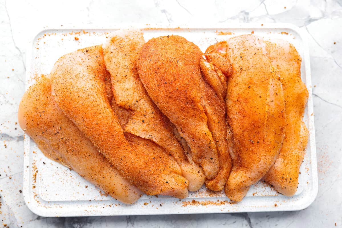 Overhead shot of chicken cutlets covered in seasoning. 