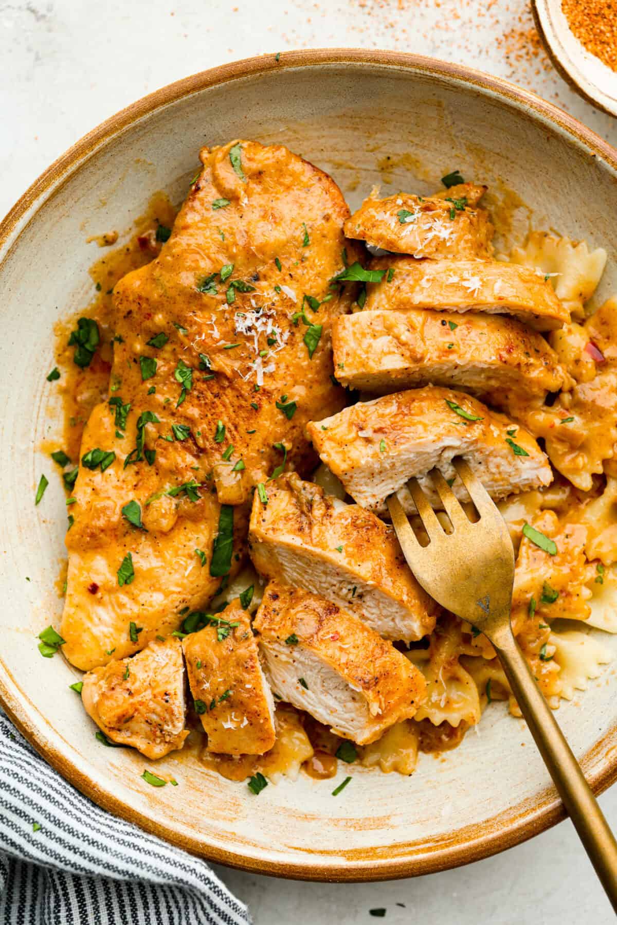 Overhead shot of plated creamy cajun chicken over bowtie pasta. 