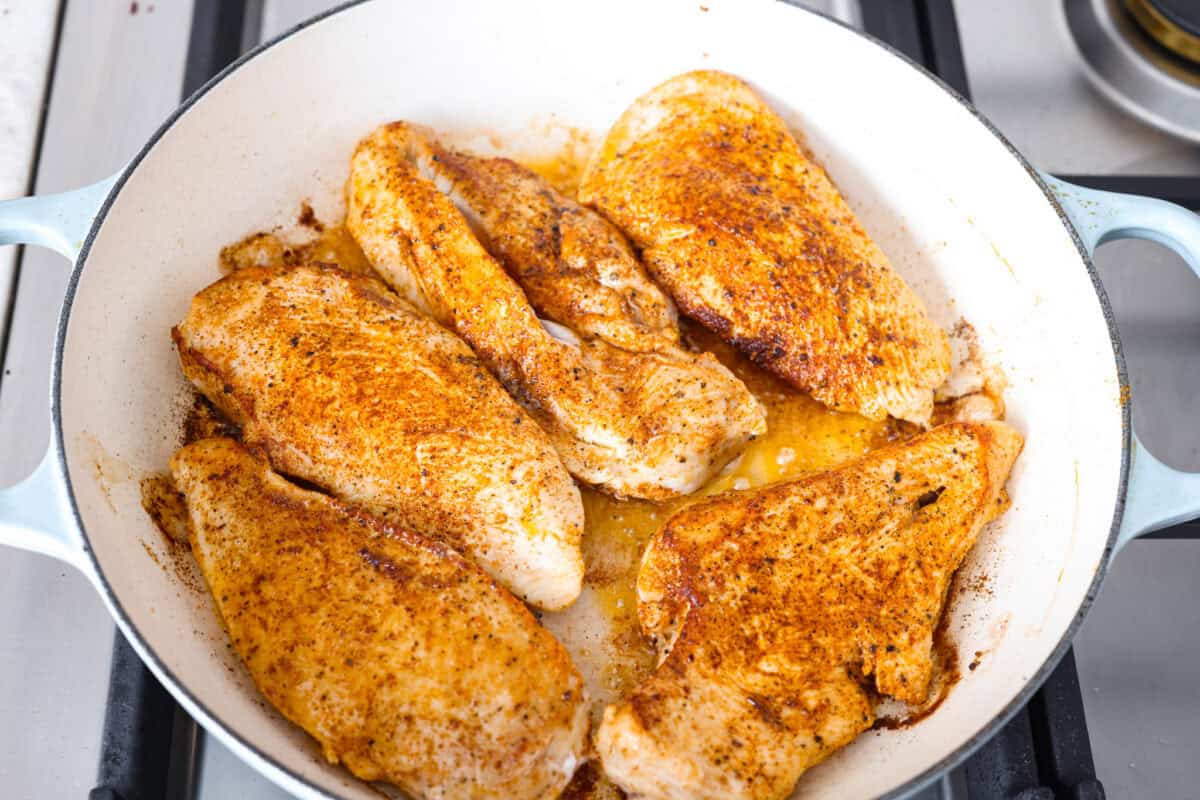 Overhead shot of seasoned chicken cooking in a skillet. 