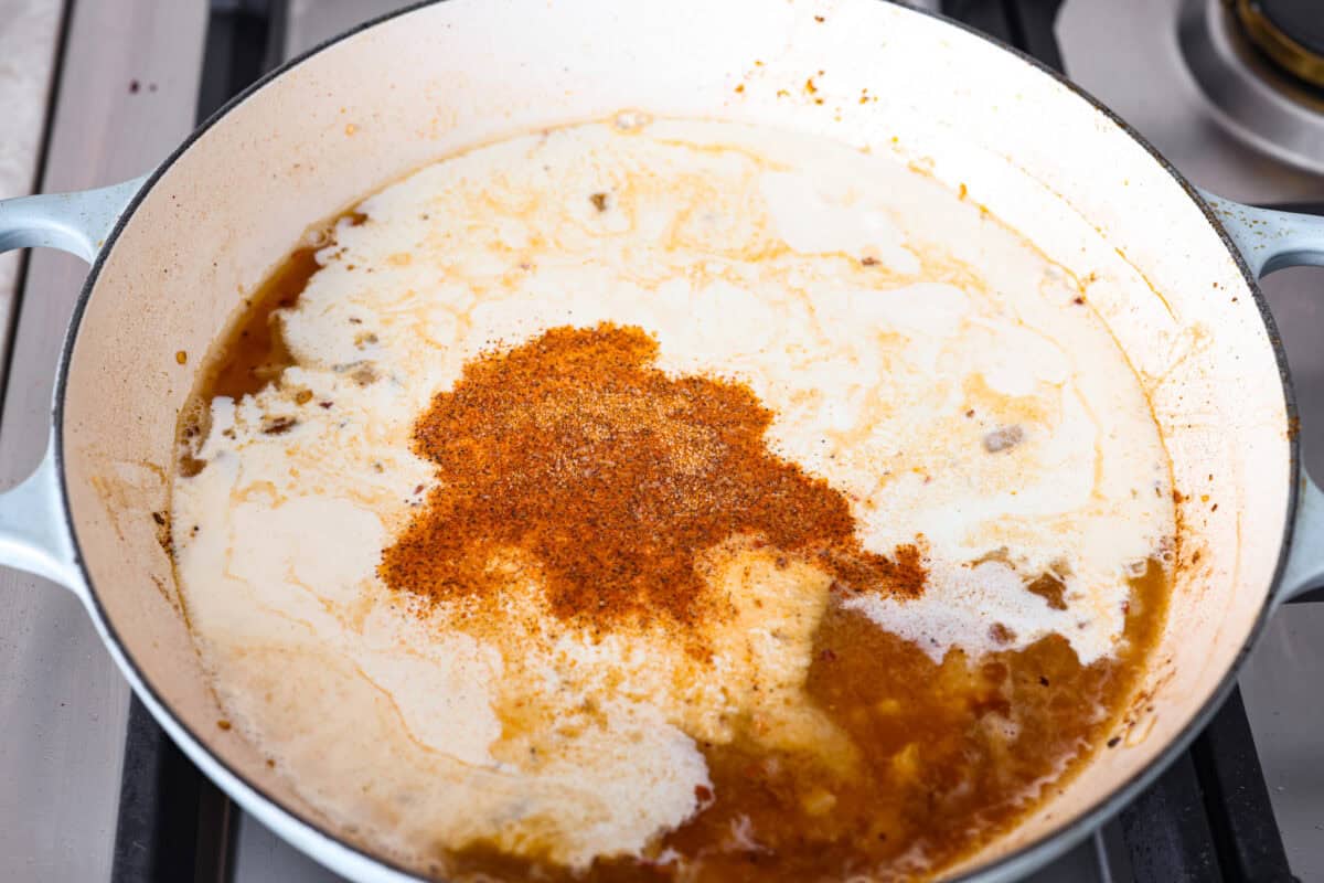 Angle shot of cream, broth, cheese and seasonings added to the skillet. 