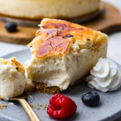 Creme brulee cheesecake on a plate with whipped cream.