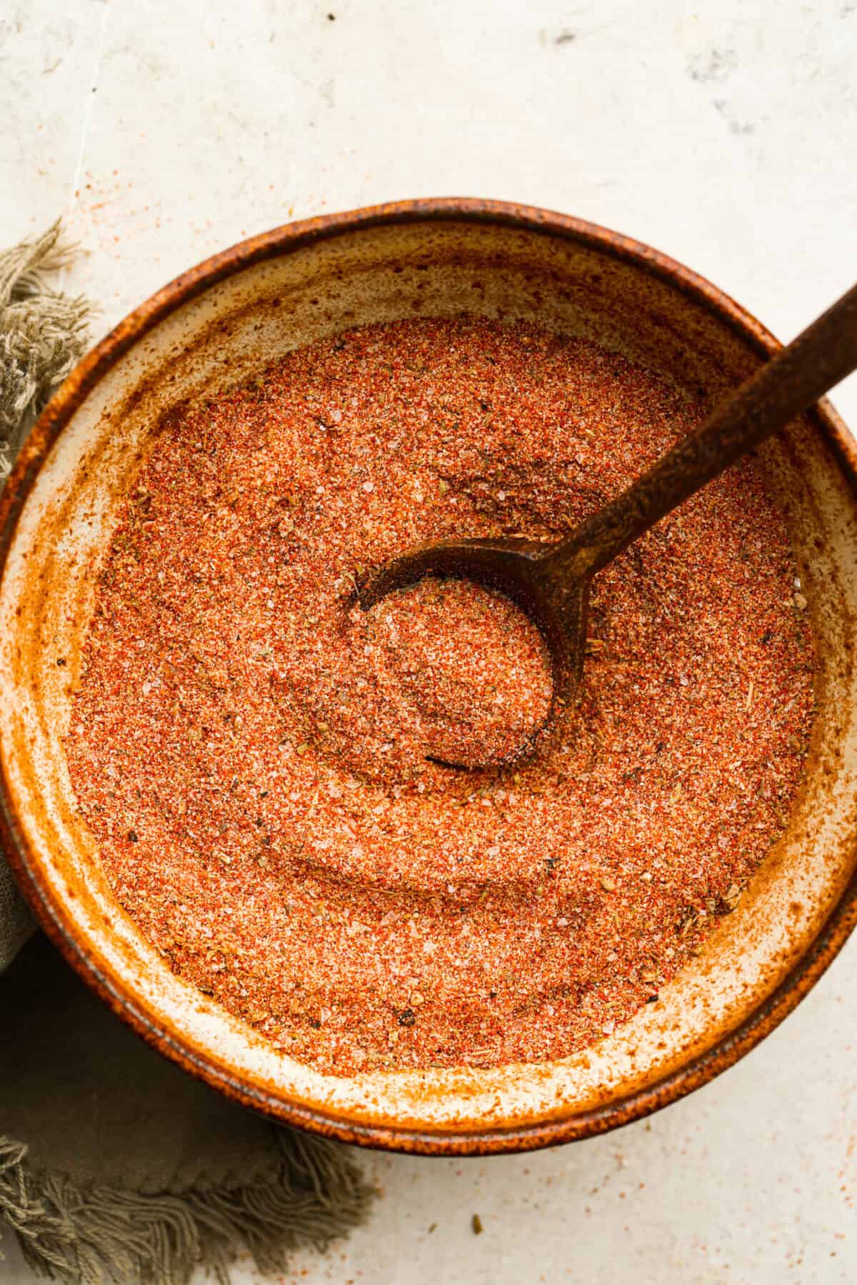 Overhead shot of creole seasoning in a bowl with a small wooden spoon. 