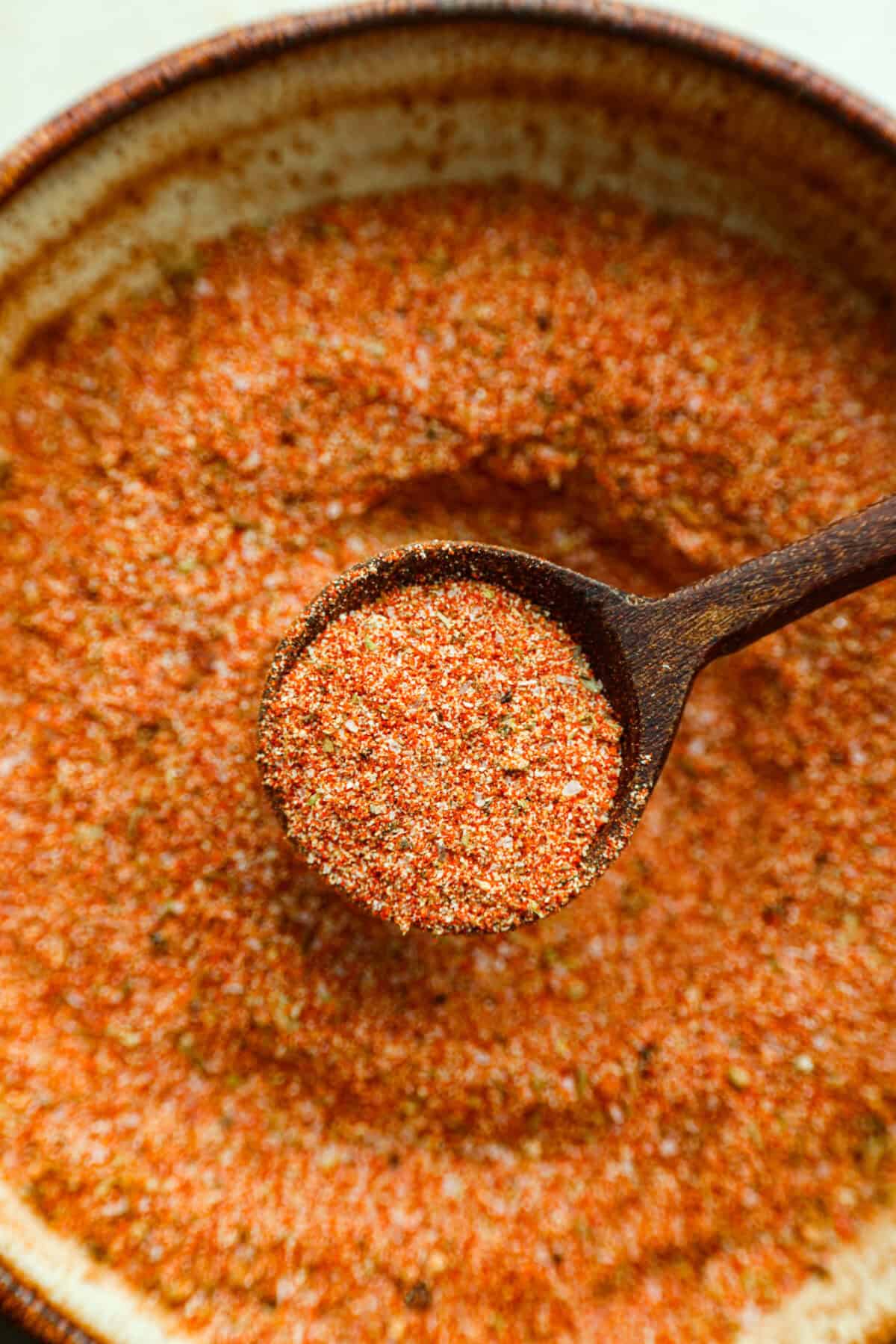 Close up shot of a scoop of creole seasoning in a small wooden spoon. 