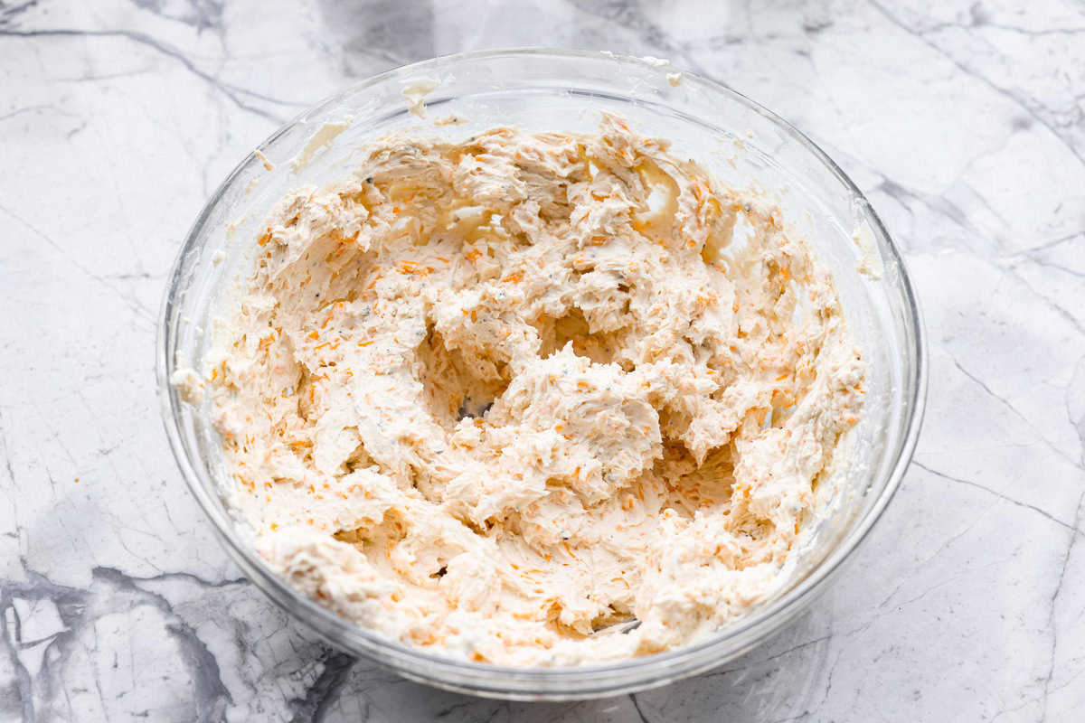 This everything bagel cheese ball combines the creamy richness of cheese with the savory blend of everything bagel seasoning! It's an irresistible appetizer you can serve with crackers, bagel chips, or veggies! Everyone will love it! Overhead shot of cheese ball ingredients mixed in a bowl.