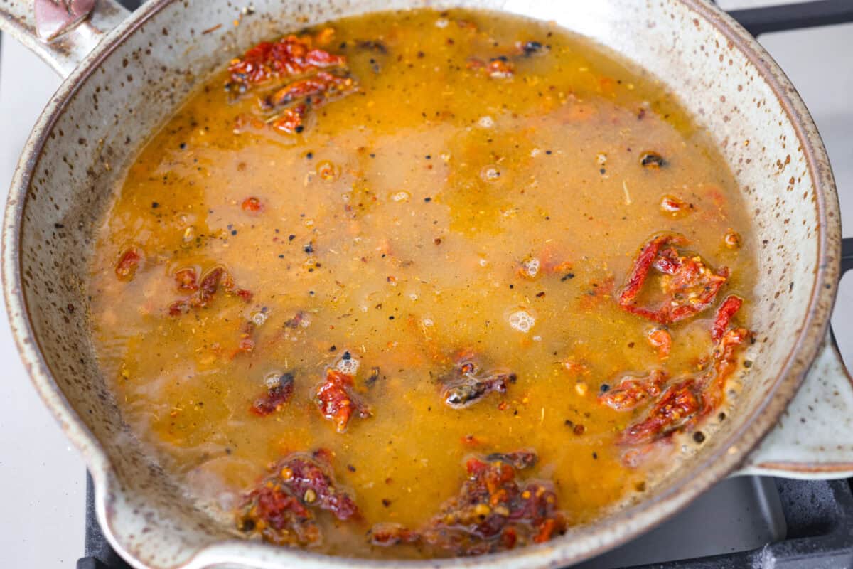 Overhead shot of chicken broth added to the sun-dried tomato mixture. 