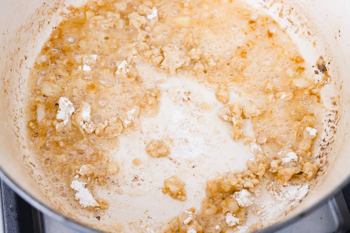 Warm and comforting, this cozy Swedish meatball soup is the perfect meal for chilly days. Juicy meatballs simmer in a rich, savory broth with tender noodles, making every spoonful satisfying. It’s easy to make and sure to become a family favorite! Overhead shot of onions cooking in a pot with butter, garlic, and flour. Creating a roux for the base of Swedish meatball soup.