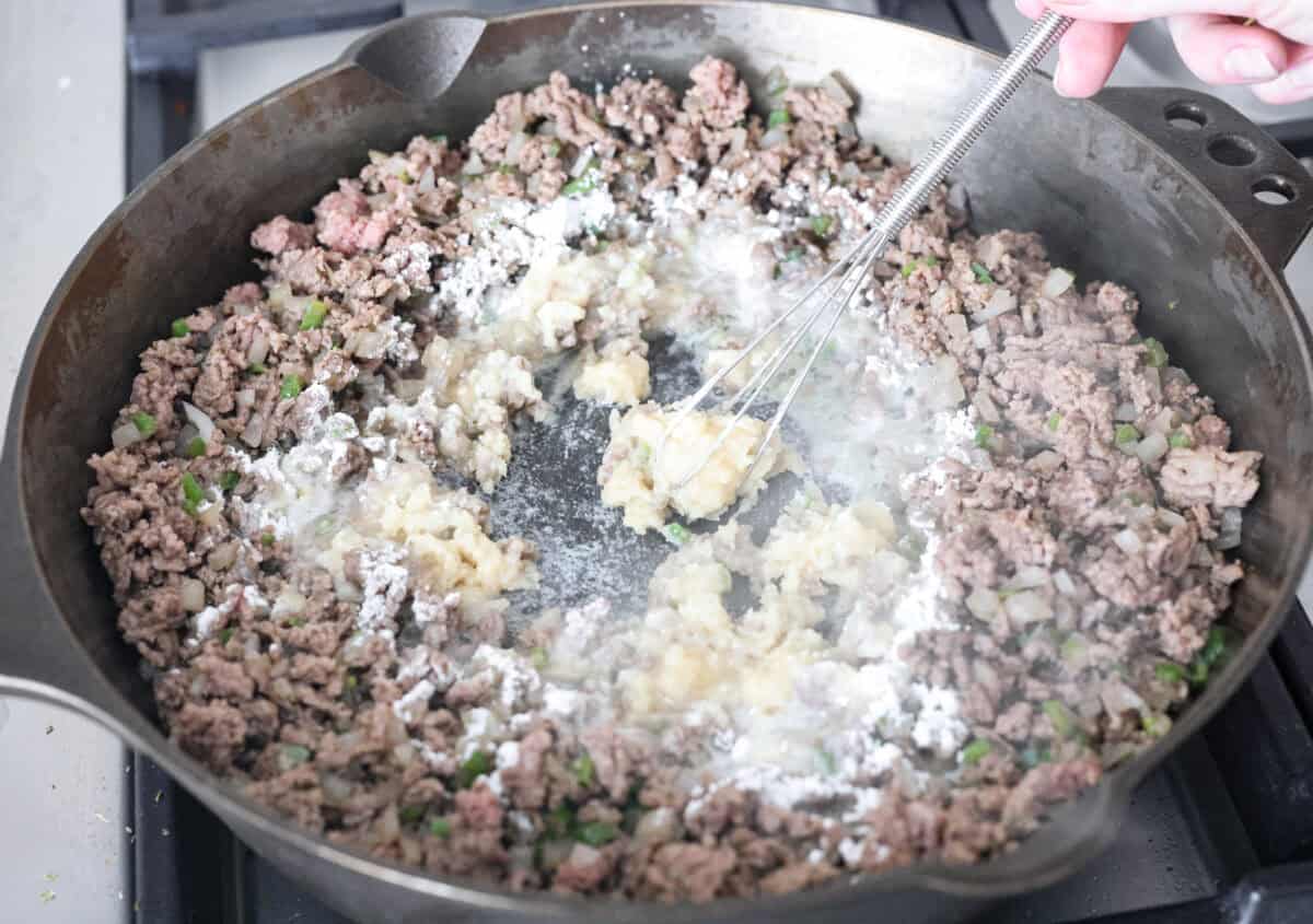 Butter and flour being whisked into the ground beef mixture. 