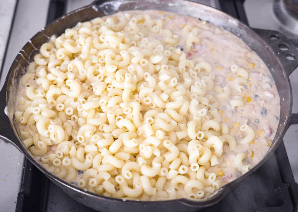 Creamy, cheesy Cowboy Mac and Cheese gets a bold twist with hearty additions like seasoned meat, tomatoes, jalapeños, corn, beans, and onions. It's rich, flavorful, and just the right amount of spice! The heat is warm but not overwhelming. If you like it spicy, add more jalapeños! Cooked noodles are added to the skillet with the cheesy, creamy beef mixture.
