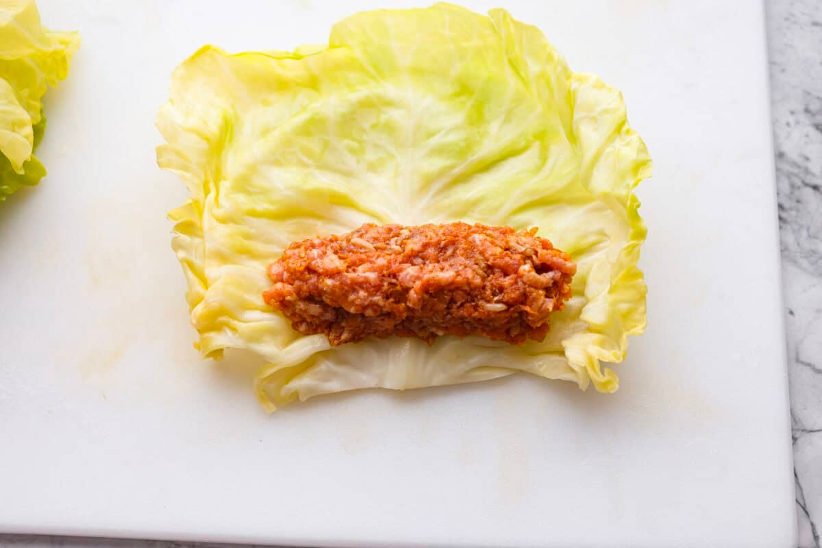 Overhead shot of a cabbage leaf with a log of filling near the edge. 