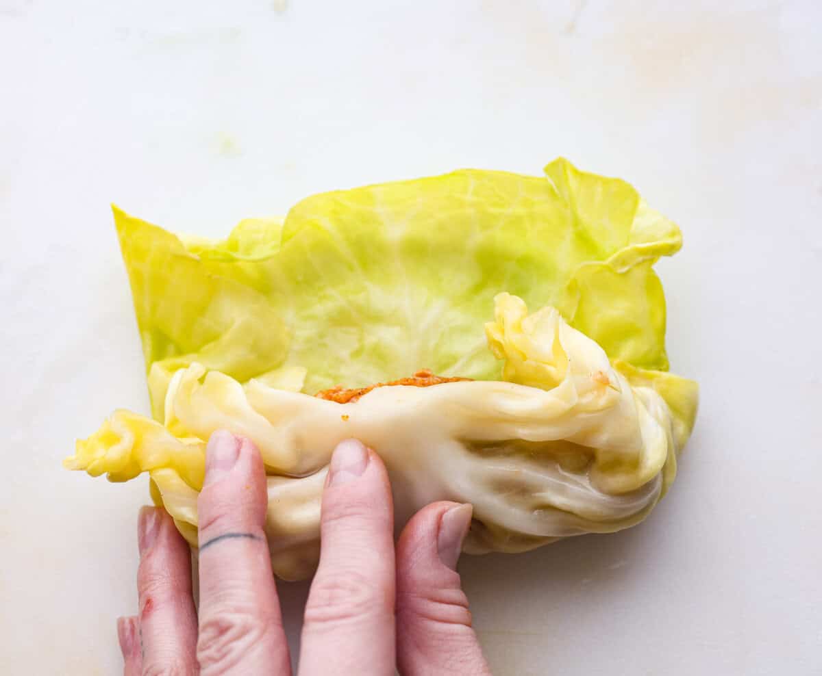 Hungarian cabbage rolls are packed with rich, hearty flavors in every bite! I know you love a good cabbage roll and can’t get enough of my Hungarian goulash, so I knew this recipe would be perfect. Close up shot of someone rolling up the filling in the cabbage leaf.