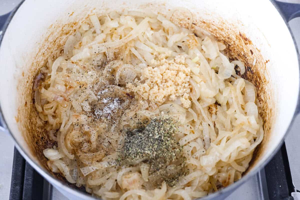 Overhead shot of onions with seasonings and garlic added to them.