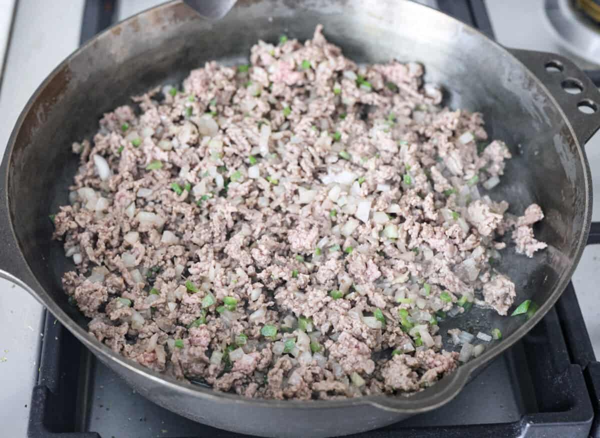 Ground beef, onions and jalapeños cooking in a skillet. 